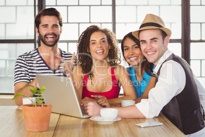 Smiling friends standing around laptop