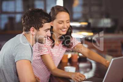 Smiling friends pointing and looking at laptop screen