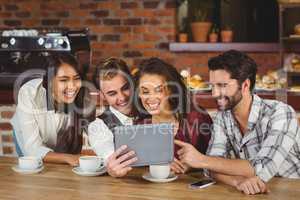 Smiling friends looking at digital tablet