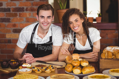 Smiling waiter and waitress leaning on counter