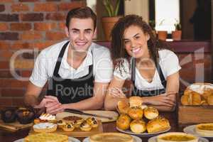 Smiling waiter and waitress leaning on counter