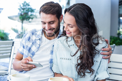 Cute couple sitting in cafe looking at smartphone