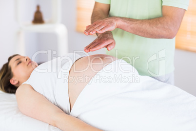 Relaxed pregnant woman getting reiki treatment