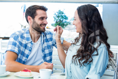 Young happy couple feeding each other with cake