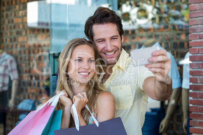 Smiling couple with shopping bags taking selfies