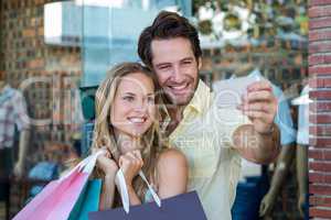Smiling couple with shopping bags taking selfies