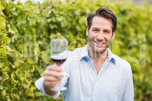 Young happy man smiling at camera and holding a glass of wine