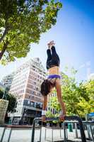 Athletic woman performing handstand on bar