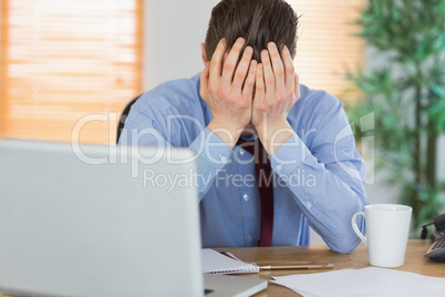 Stressed businessman with head in hands