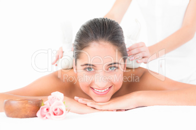 Beautiful brunette enjoying a herbal compress massage