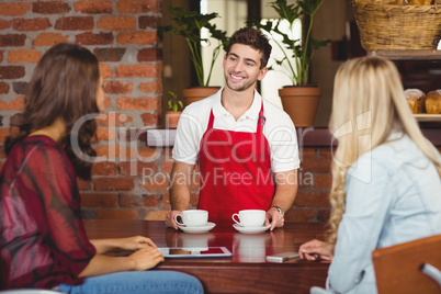 Smiling waiter serving coffees to customers