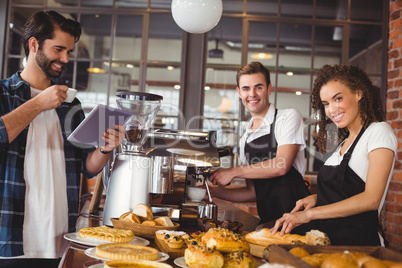 Smiling colleagues serving customer with tablet and coffee