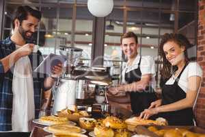 Smiling colleagues serving customer with tablet and coffee