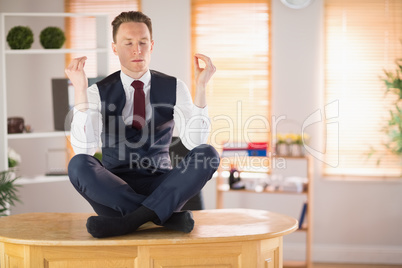 Calm businessman meditating in lotus pose