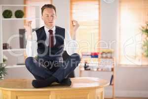 Calm businessman meditating in lotus pose