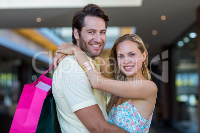 Smiling couple with shopping bags embracing