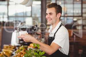 Smiling barista offering cup of coffee
