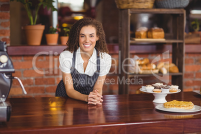 Smiling barista leaning on counter