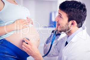 Doctor examining stomach of standing pregnant patient