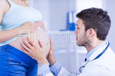 Doctor checking stomach of standing pregnant patient