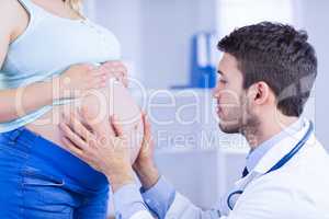 Doctor checking stomach of standing pregnant patient