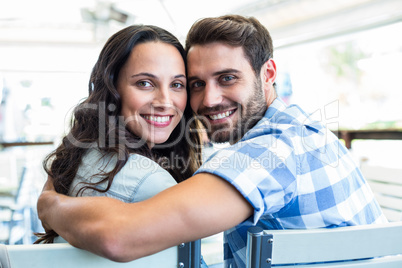 Cute couple sitting outside a cafe smiling at camera