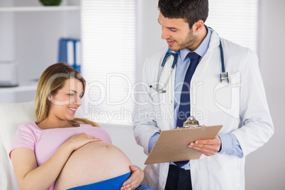 Smiling doctor giving advice to lying pregnant patient