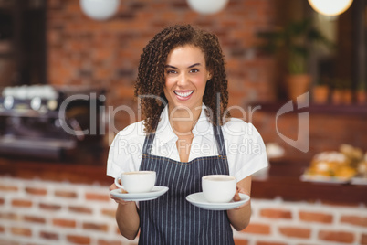 Smiling barista serving two cups of coffee