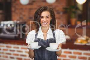Smiling barista serving two cups of coffee