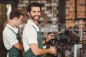 Two smiling baristas preparing coffee