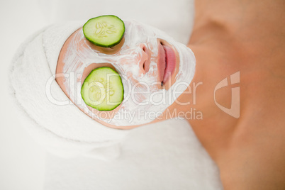 Relaxed woman with cucumber on a creamed face