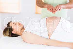 Relaxed pregnant woman getting reiki treatment