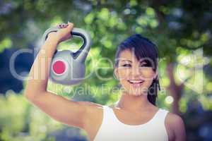 Portrait of smiling athletic woman lifting kettlebell