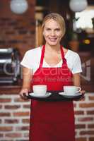 Pretty waitress holding a tray with coffees