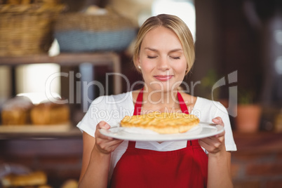 Pretty waitress smelling a plate of cake