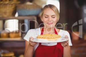 Pretty waitress smelling a plate of cake