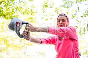 A pretty woman in a pink outfit doing exercise with a weight