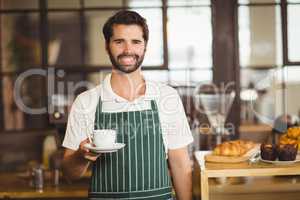 Smiling barista holding a cup of coffee