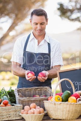 Smiling farmer holding two red apples