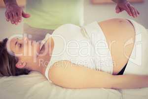 Relaxed pregnant woman getting reiki treatment