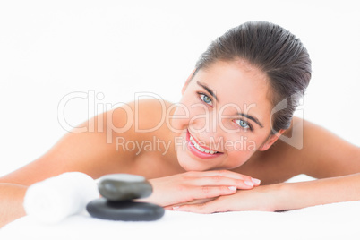 A portrait smiling pretty brunette on massage table with stones