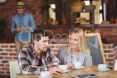 Two smiling friends talking and drinking coffee