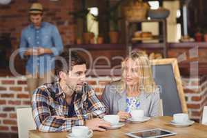 Two smiling friends talking and drinking coffee