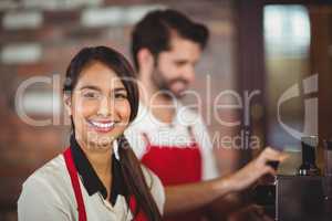 Smiling waitress using the coffee machine