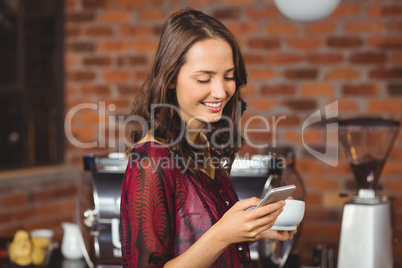 Pretty woman holding a cup of coffee and texting