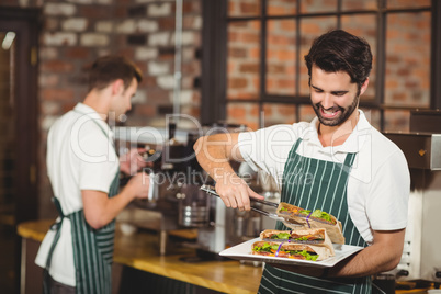 Smiling waiter picking a sandwich