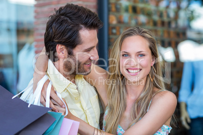 Smiling couple with shopping bags embracing