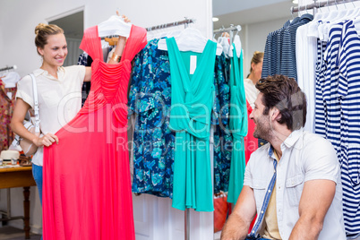 Smiling woman showing red dress to boyfriend Smiling woman showing red dress to boyfriend