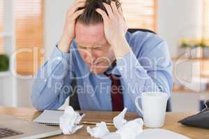 Stressed businessman with head in hands