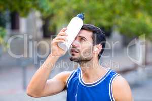 An handsome athlete leaning a bottle against his head